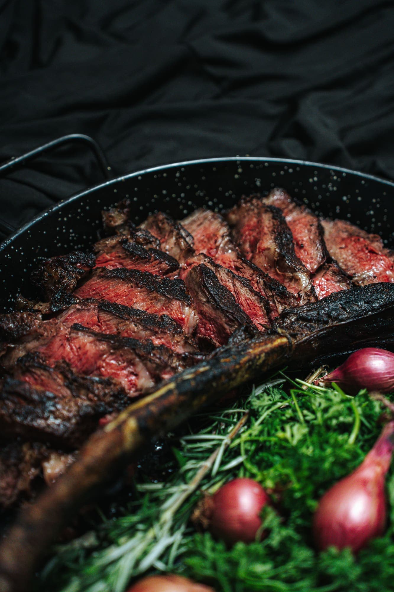 Sliced tomahawk in cast iron with herbs and shallots