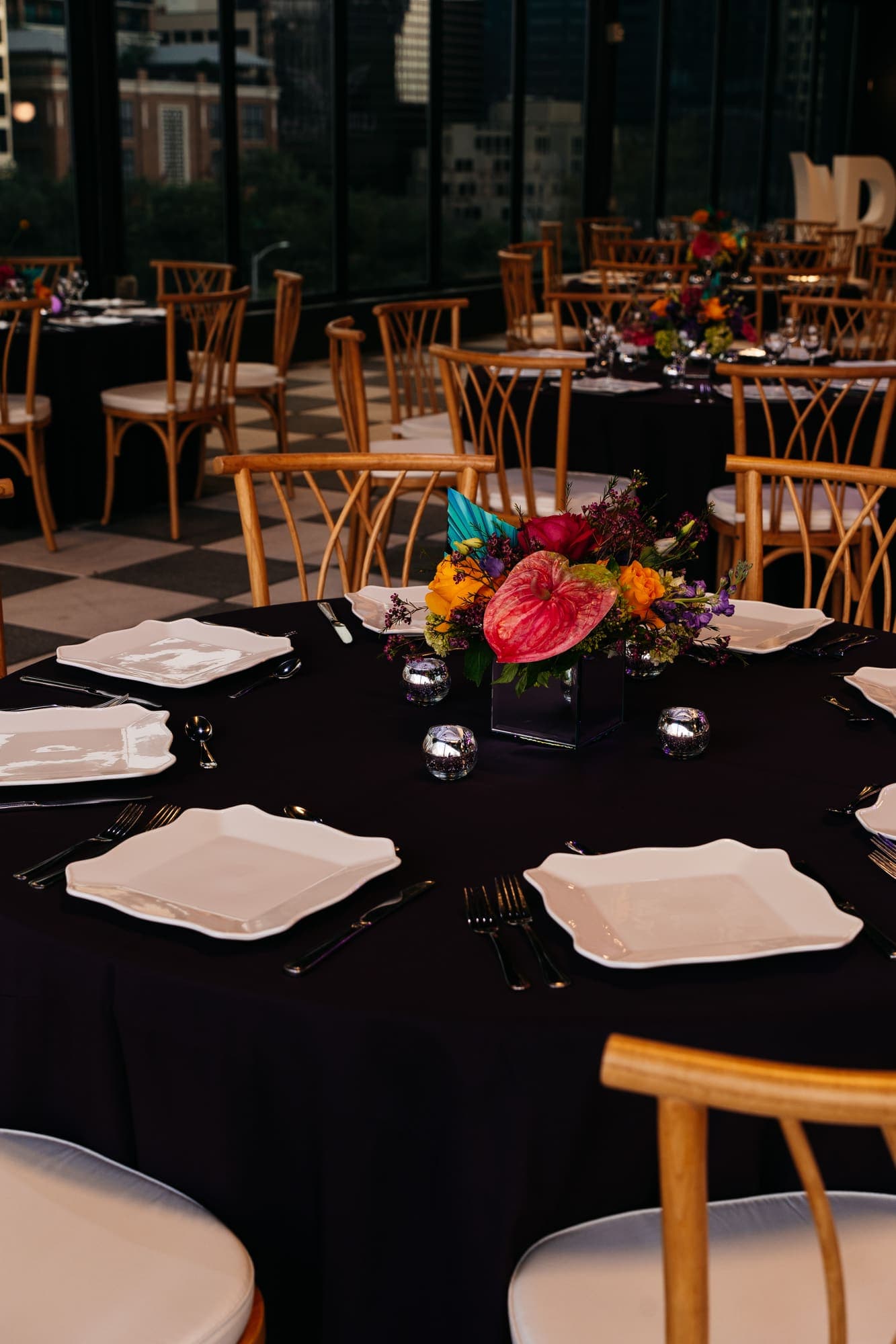 Reception tables set with white plates, candles, and bright florals
